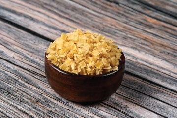 A bowl of white potato dices on a wooden table